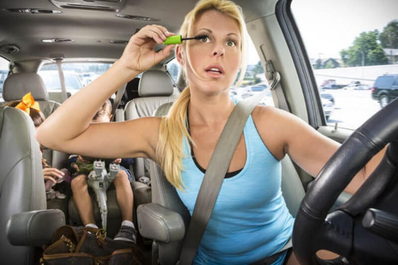 busy woman applying her makeup while driving